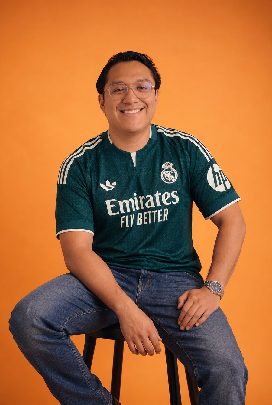 Marcos, el geek, sonriendo sentado en un banco sobre fondo naranja